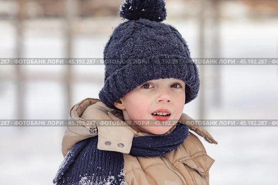 Portrait of cute little boy in beige winter clothes walks in winter park during a snowfall. Baby having fun. Cute child in a warm hat and scarf soiled in the snow. Outdoors winter activities for kids. Стоковое фото, фотограф Ирина Михайличенко / Фотобанк Лори