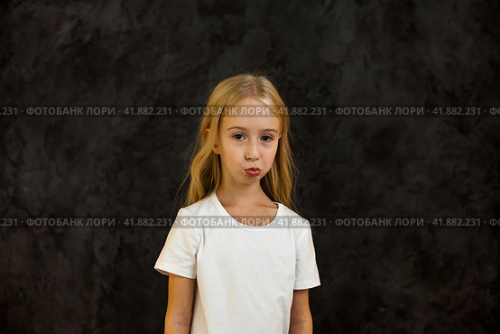 Portrait of frowning cover girl kid model 6 year old in white t-shirt expression emotion, angry looking at camera. Scowl child posing at black, studio shot. Kids emotional concept. Copy ad text space. Стоковое фото, фотограф Aleksandr Golubev / Фотобанк Лори