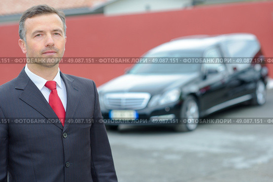 Portrait of funeral director standing in front of hearse. Стоковое фото, агентство Ingram Publishing / Фотобанк Лори