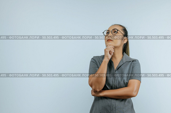Portrait of Serious Asian woman glasses 30s in casual clothes looking aside and put hand prop up on chin isolated on wall background in studio. Mock up copy space. Стоковое фото, агентство Ingram Publishing / Фотобанк Лори