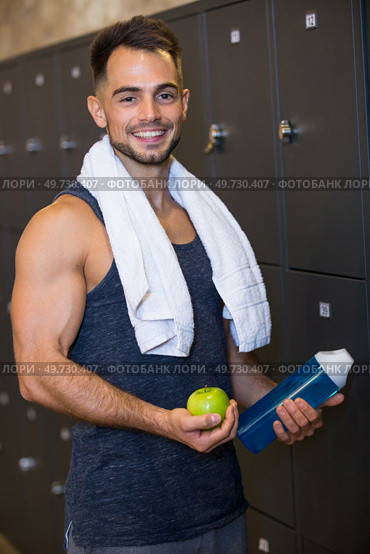 portrait of sportsman holding water and apple in locker room. Стоковое фото, агентство Ingram Publishing / Фотобанк Лори