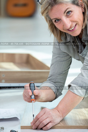 portrait of woman fitting laminated floor boards. Стоковое фото, агентство Ingram Publishing / Фотобанк Лори