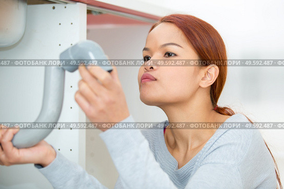 portrait of woman looking at plumbing fittings. Стоковое фото, агентство Ingram Publishing / Фотобанк Лори
