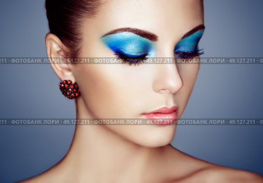 Portrait of young beautiful woman with blue makeup. Face Girl with earring close up. Fashion jewelry. Стоковое фото, агентство Ingram Publishing / Фотобанк Лори