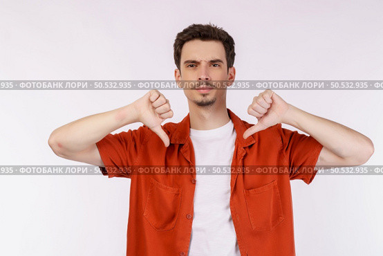 Portrait of young man shows sign of dislike, looks with negative expression and disapproval on isolated background. Disagreement, disgust and negative expressions. Стоковое фото, агентство Ingram Publishing / Фотобанк Лори