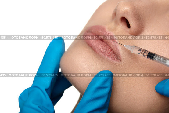 Portrait of young woman getting cosmetic injection of botox, isolated over white background. Стоковое фото, агентство Ingram Publishing / Фотобанк Лори