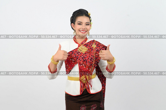 Portrait Young beautiful woman dress up in Thai northeastern region, standing with smile and thumb up, copy space for insert advertise product on white background. Стоковое фото, агентство Ingram Publishing / Фотобанк Лори