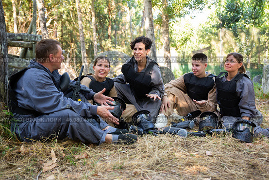 Positive paintball players sitting on battleground and chatting. Стоковое фото, фотограф Яков Филимонов / Фотобанк Лори