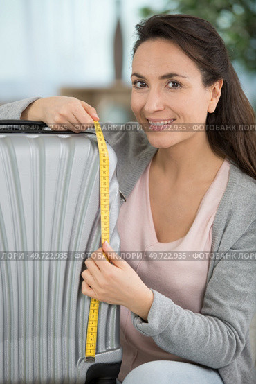 positive woman is measuring her suitcase. Стоковое фото, агентство Ingram Publishing / Фотобанк Лори