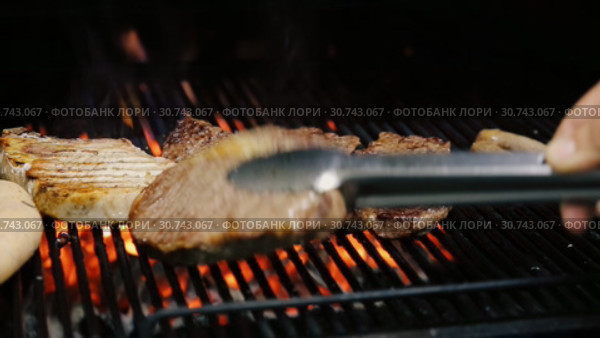 Повар переворачивает мясо на решетке гриля. Стоковое видео, видеограф Алексей Кокорин / Фотобанк Лори