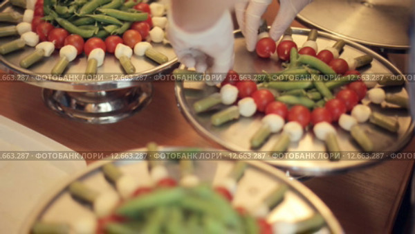 Повар ставит на большой поднос канапе с помидорами, моцареллой и соусом. Стоковое видео, видеограф Denis Mishchenko / Фотобанк Лори