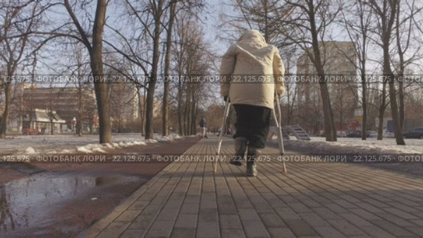 Пожилая женщина на костылях в городском парке весной (2016 год). Редакционное видео, видеограф Серёга / Фотобанк Лори