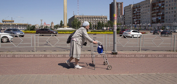 Пожилая женщина передвигается по улице с помощью ходунков. Липецк. (2023 год). Стоковое фото, фотограф Евгений Будюкин / Фотобанк Лори