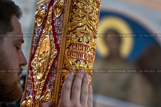 Православный священнослужитель держит Святое Евангелие во время службы в храме (2019 год). Редакционное фото, фотограф Николай Винокуров / Фотобанк Лори