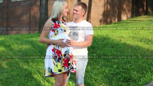 Pregnant woman and happy man pose in summer green park. Стоковое видео, видеограф Светлана Додух / Фотобанк Лори