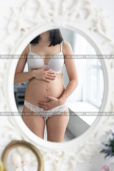 pregnant woman checking herself mirror. Стоковое фото, агентство Ingram Publishing / Фотобанк Лори