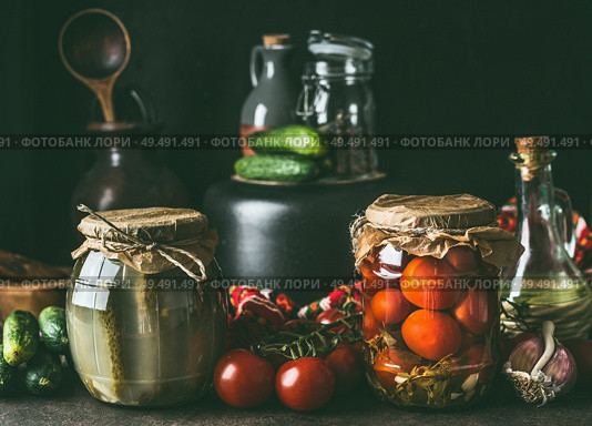 Preserving of fruits and vegetables harvest. Various preserve glass jars on dark table. Healthy way of harvest storage. Стоковое фото, агентство Ingram Publishing / Фотобанк Лори