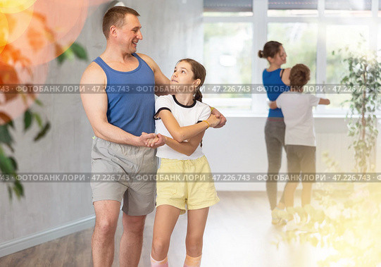 Preteen daughter learning dynamic boogie-woogie in pair with his young father in dance studio during family class. Стоковое фото, фотограф Яков Филимонов / Фотобанк Лори