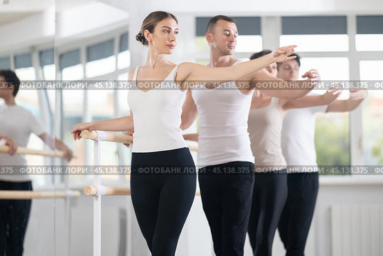 Pretty young girl in black and white sportswear, participating 2nd position of ballet stance at barre with group in choreography studio. Стоковое фото, фотограф Яков Филимонов / Фотобанк Лори