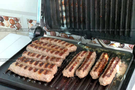 Приготовление чевапчичи (колбасок) на электрическом гриле - Cooking chevapchichi (sausage) on an electric grill. Стоковое фото, фотограф Владислав Дельдюгинов / Фотобанк Лори
