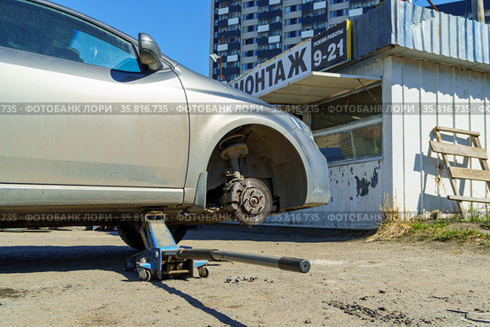 Приподнятый автомобиль на домкрате без колеса в шиномонтаже на улице (2021 год). Стоковое фото, фотограф Sergei Gorin / Фотобанк Лори