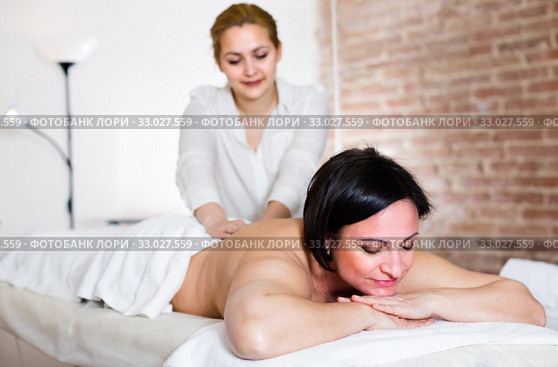 Professional masseuse is doing massage of back and loin to adult woman. Стоковое фото, фотограф Яков Филимонов / Фотобанк Лори