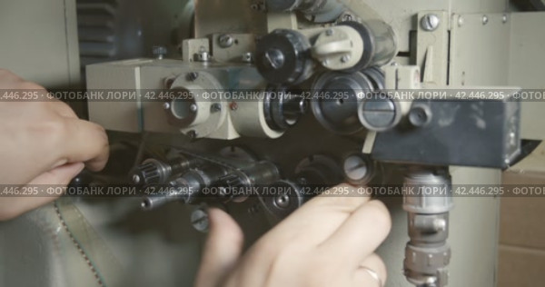 Projectionist insert 35 mm film strip into a film projector. Start up of a movie projector. Close-up operator hands. Стоковое видео, видеограф EStarodubov / Фотобанк Лори