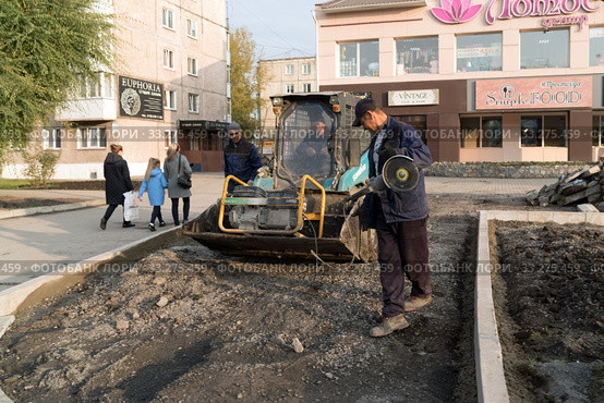 Рабочие подготавливают землю к укладке асфальта перед магазином в жилом районе города Ачинск. Красноярский край. Россия. (2019 год). Редакционное фото, фотограф Светлана Попова / Фотобанк Лори