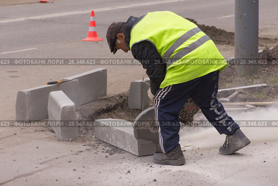 Рабочий отрезает кусок бордюра дисковой пилой (2018 год). Редакционное фото, фотограф Дмитрий Рыженков / Фотобанк Лори