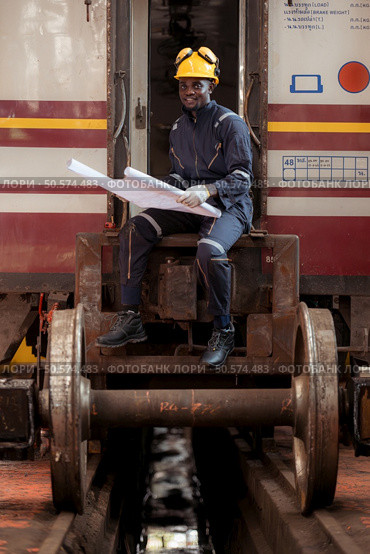 Railway technician in uniform and helmet inspect the train wheels removed from the locomotives in the train workshop. Стоковое фото, агентство Ingram Publishing / Фотобанк Лори