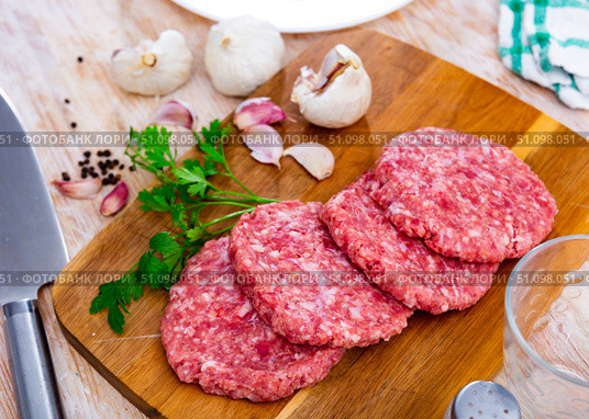 Raw hamburger patties on wooden board with condiments. Стоковое фото, фотограф Яков Филимонов / Фотобанк Лори