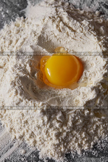 Raw organic egg and white flour on the kitchen table. Preparation for kneading the dough. Raw egg and flour on the kitchen table, staged cooking dough. Стоковое фото, агентство Ingram Publishing / Фотобанк Лори
