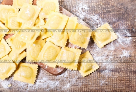 Raw ravioli with flour on wooden table. Стоковое фото, агентство Ingram Publishing / Фотобанк Лори