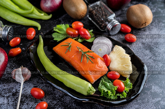Raw salmon fillets, pepper, kiwi, pineapples, and rosemary onto a plate and black cement floor. Стоковое фото, агентство Ingram Publishing / Фотобанк Лори