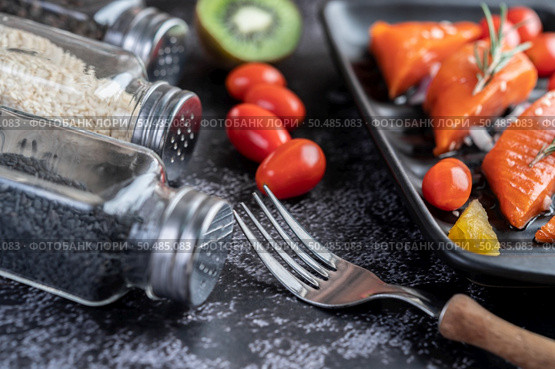 Raw salmon fillets, pepper, kiwi, pineapples, and rosemary onto a plate and black cement floor.Selective focus fork. Стоковое фото, агентство Ingram Publishing / Фотобанк Лори
