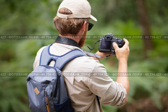 rear view of male backpacker using camera in rural setting. Стоковое фото, агентство Ingram Publishing / Фотобанк Лори