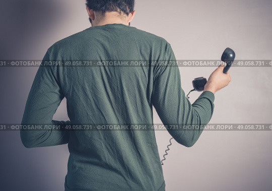 Rear view shot of a young man using a vintage rotary telephone. Стоковое фото, агентство Ingram Publishing / Фотобанк Лори