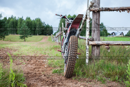 Recreational off-road motorcycle leaning to rural wooden fence in village, rear view. Стоковое фото, фотограф Кекяляйнен Андрей / Фотобанк Лори