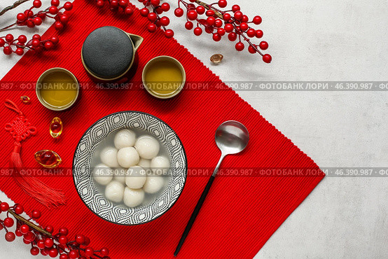 Red mat with bowl of tangyuan, tea and Chinese decor on white grunge background. Dongzhi Festival. Стоковое фото, фотограф Pixel_shot / Фотобанк Лори