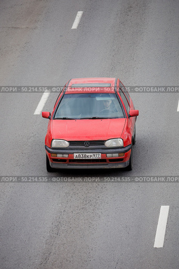 Red volkswagen golf 3 driving on asphalt road, aerial front view. Редакционное фото, фотограф Константин Григорьев / Фотобанк Лори