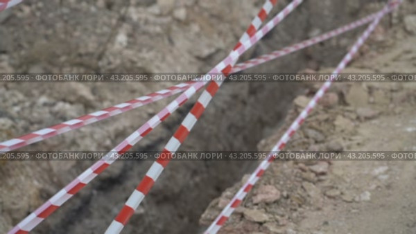 Red white barrier tape trenches. Focus on red and white barrier tape at construction site. Ribbons indicate dug trenches. Стоковое видео, видеограф svetograph / Фотобанк Лори