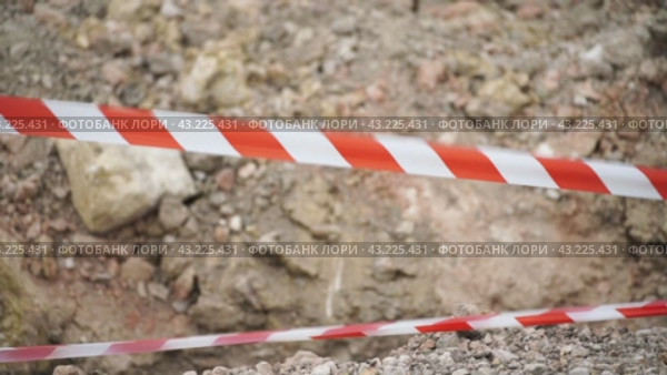 Red white barrier tape trenches. Focus on red and white barrier tape at construction site. Ribbons indicate dug trenches. Стоковое видео, видеограф svetograph / Фотобанк Лори