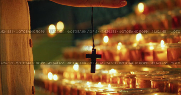 Religious cross against background of burning glowing candles in the church. Christian faith in God. Стоковое видео, видеограф Igor Tichonow / Фотобанк Лори