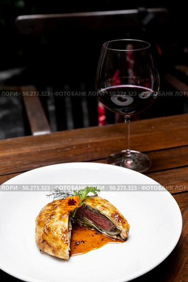 Roasted Beef Wellington with gravy brown savory sauce, international gourmet cuisine of stuff beef meat in baked bread puff with glass of red wine. Unising for recipe menu pf food and drink industry.. roasted beef wellington. Стоковое фото, агентство Ingram Publishing / Фотобанк Лори