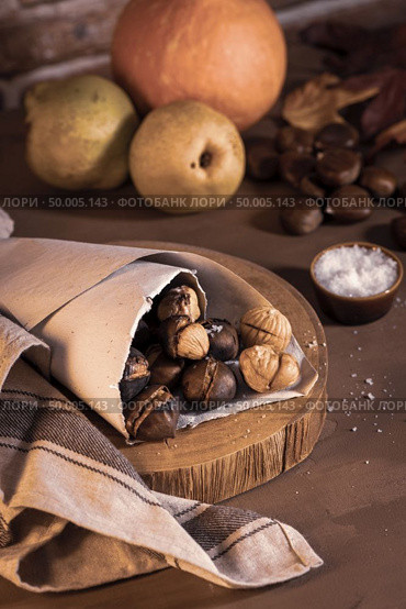 Roasted chestnuts in a paper cone, on a rustic kitchen countertop. Стоковое фото, агентство Ingram Publishing / Фотобанк Лори