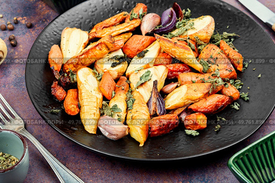 Roasted root vegetables, baked parsnip root, red onions, carrots, and garlic for a vegan dish.. Grilled oven root vegetables. Стоковое фото, агентство Ingram Publishing / Фотобанк Лори