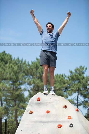 rock-climber stands triumphant at the top of artificial-wall. Стоковое фото, агентство Ingram Publishing / Фотобанк Лори