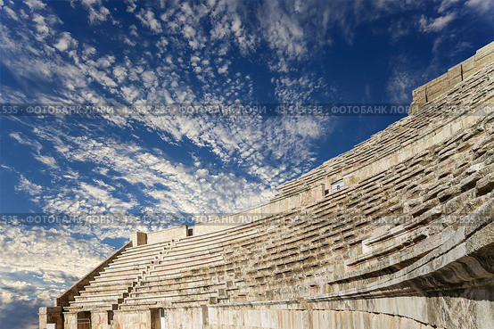 Roman Theatre in Amman, Jordan -- theatre was built the reign of Antonius Pius (138-161 CE), the large and steeply raked structure could seat about 6000 people. Against the sky with clouds (2016 год). Стоковое фото, фотограф Владимир Журавлев / Фотобанк Лори