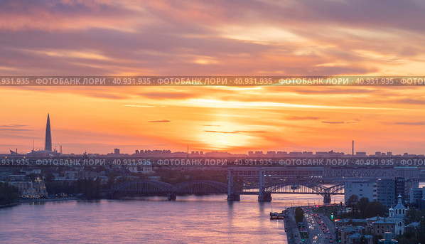Россия. Санкт-Петербург. Вид на Финляндский железнодорожный мост через Неву, Александро Невскую лавру и Лахта центр. Заход солнца над городом (2023 год). Редакционное фото, фотограф Литвяк Игорь / Фотобанк Лори