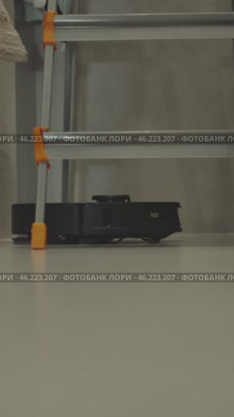 round robot vacuum moves methodically across the bathroom floor, its sensors scanning for dust and hair. Стоковое видео, видеограф Feruza Tashmetova / Фотобанк Лори
